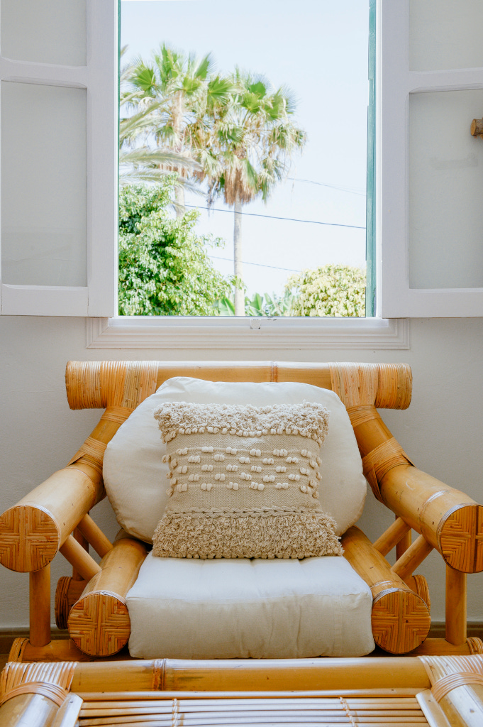 Fauteuil en bambou avec coussin près d'une fenêtre ouverte à Tenerife.
