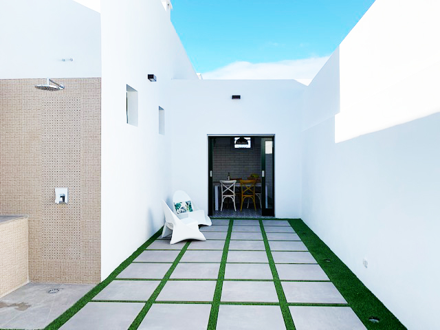 Cour intérieure moderne à Tenerife avec chaises blanches et sol carrelé.