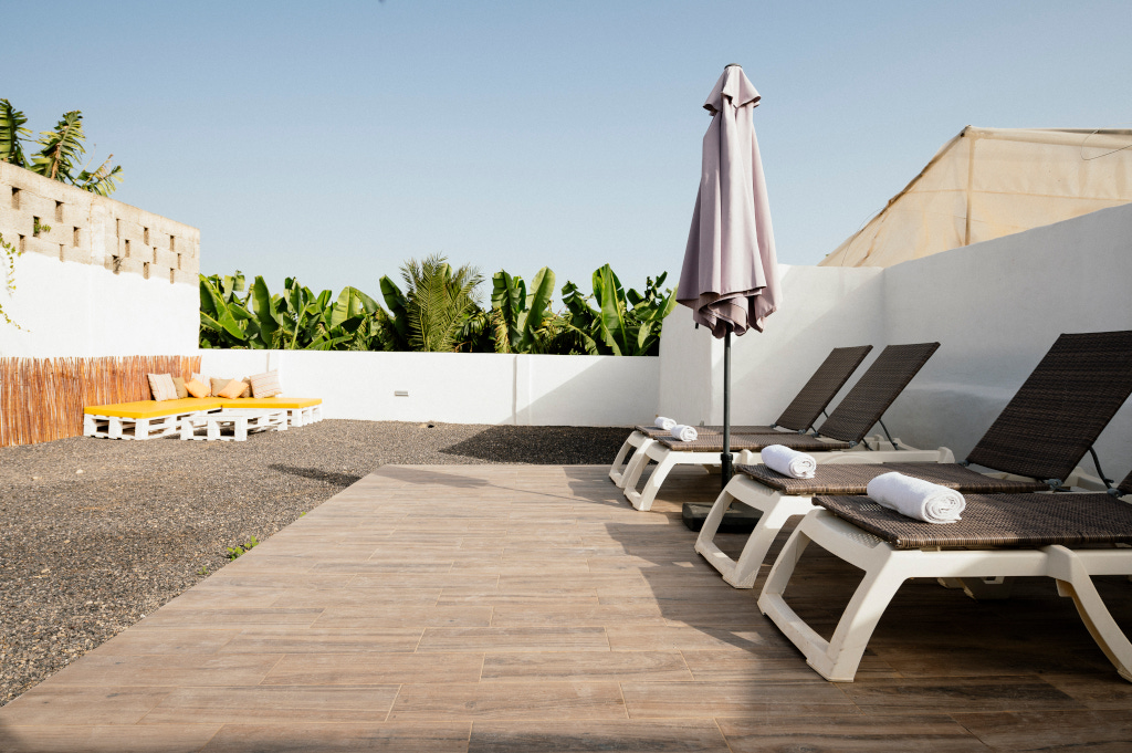 Chaises longues et parasol sur terrasse avec bananiers à Tenerife.