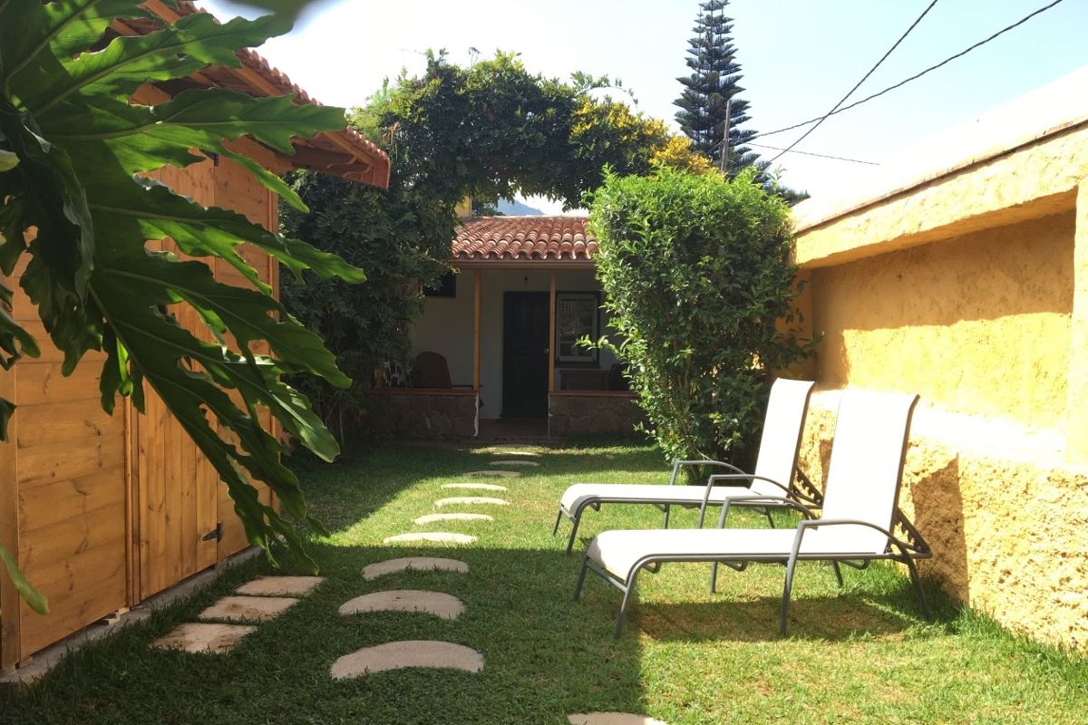 Chaises longues et jardin à Tenerife avec chemin pavé vers une maison.