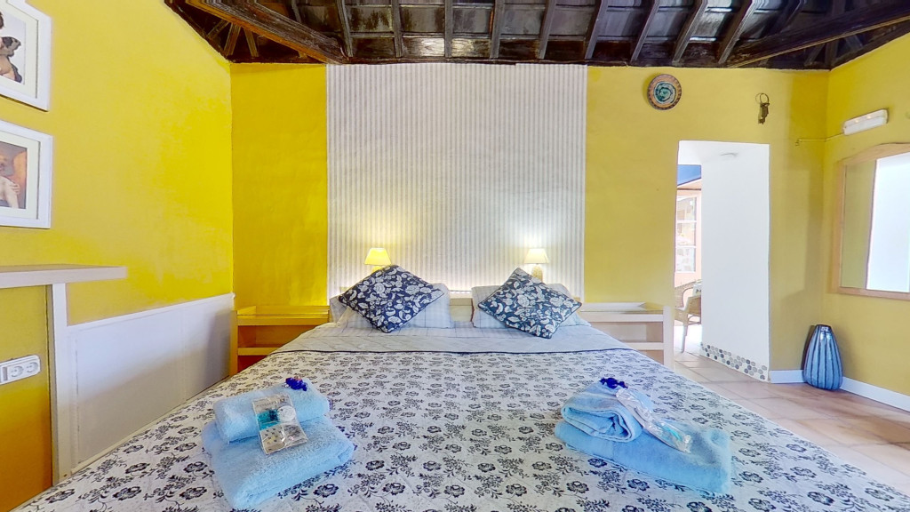 Chambre à coucher avec lit double, murs jaunes et décoration bleue à Tenerife.
