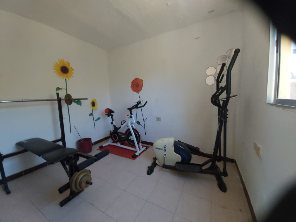 Salle de sport intérieure avec vélo elliptique et banc de musculation à Tenerife.