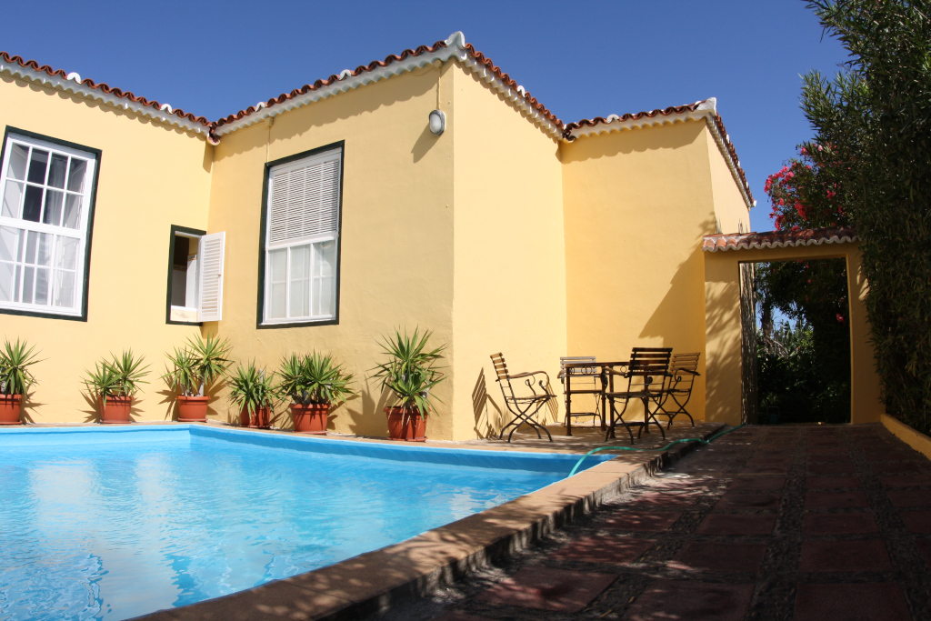 Maison jaune avec piscine et plantes en pot à Tenerife.