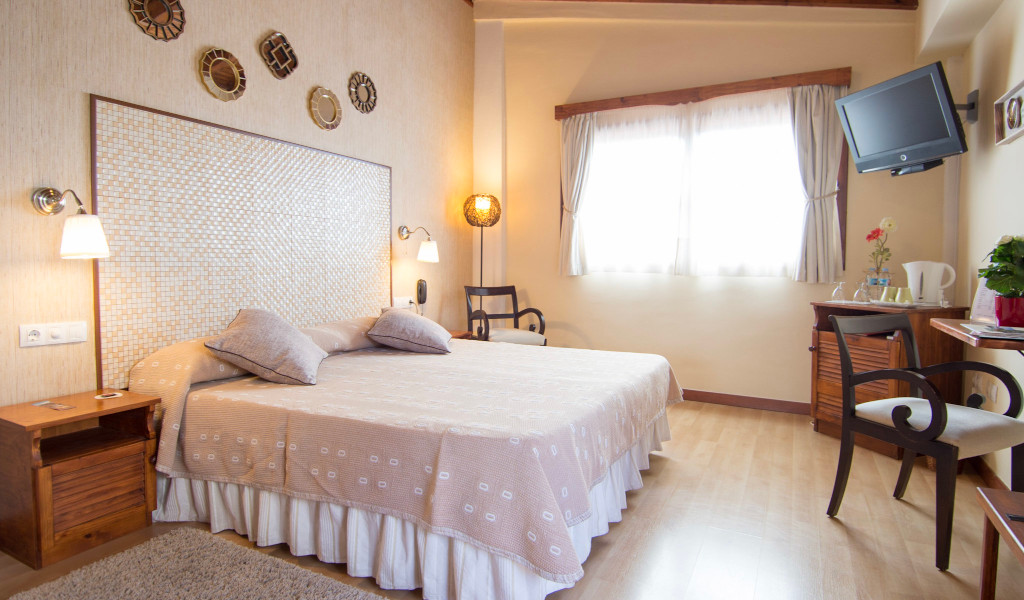 Chambre d'hôtel lumineuse à Tenerife avec lit double, bureau et télévision.