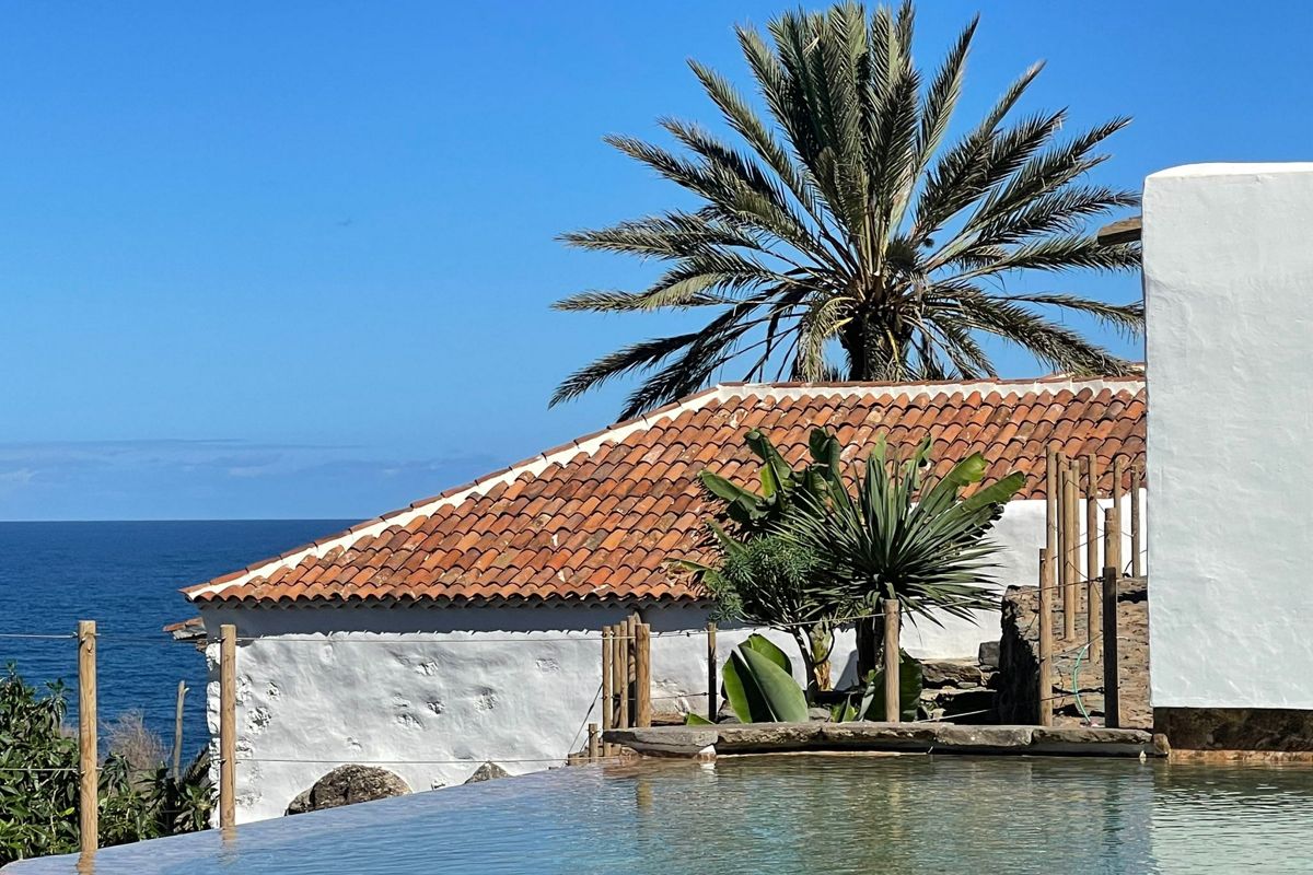 Toit en tuiles rouges avec palmier et mer à Tenerife.