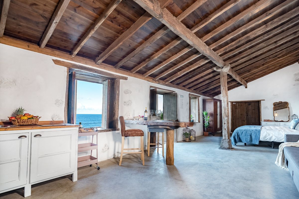Intérieur de chambre avec vue sur mer à Tenerife, meuble en bois et lit au fond.