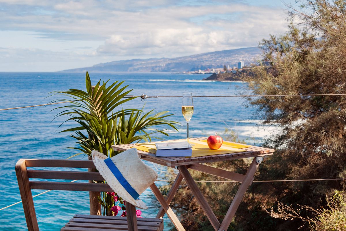 Table en bois avec verre de vin, livre et pomme, vue sur la mer à Tenerife.