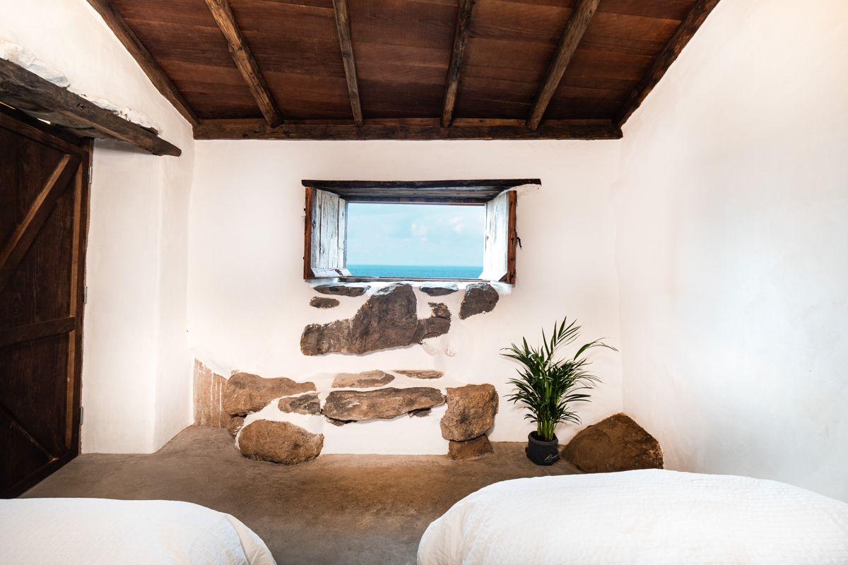 Chambre avec fenêtre vue mer, mur en pierre et plante à Tenerife.