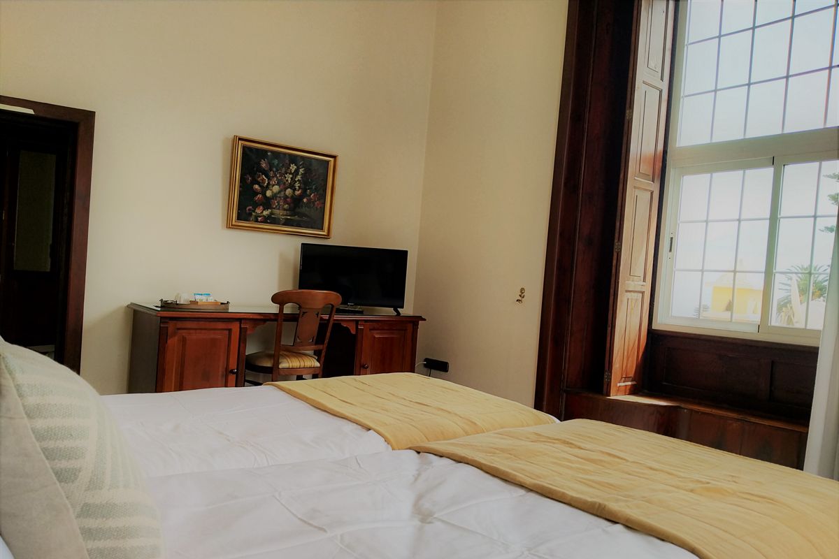 Chambre avec lit, bureau, chaise, télévision et fenêtre à Garachico, Tenerife.