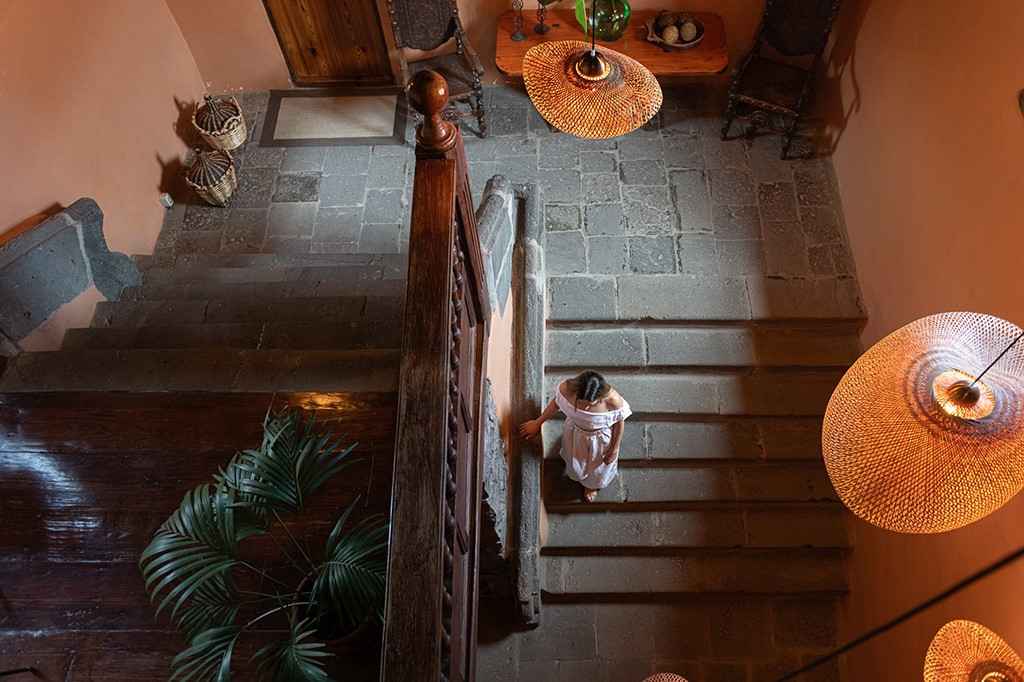 Femme en robe blanche descendant un escalier à Tenerife, près de luminaires suspendus.