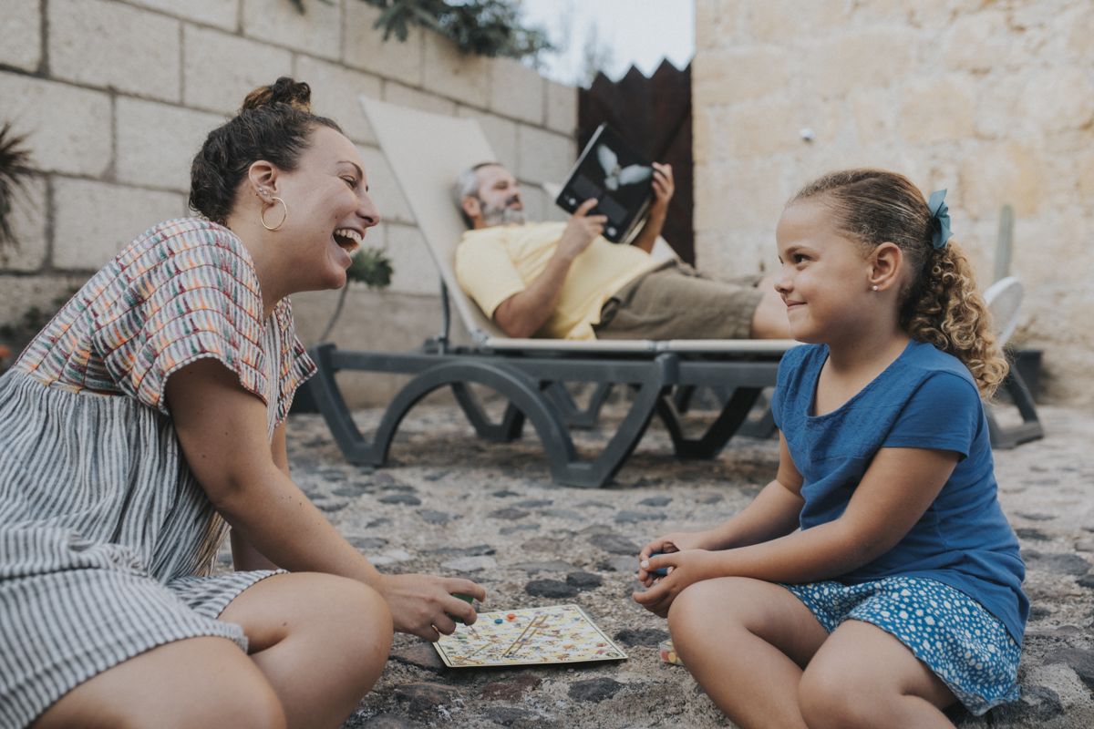 Personnes jouant à un jeu de société à Tenerife, avec un homme lisant en arrière-plan.