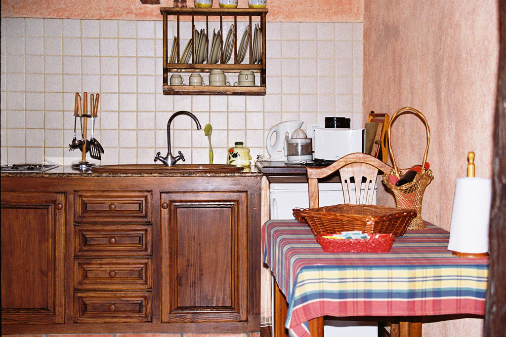 Cuisine rustique avec évier, table à carreaux, vaisselle et paniers à Tenerife.