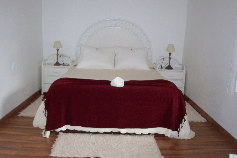 Lit double avec couverture bordeaux dans une chambre à Tenerife.