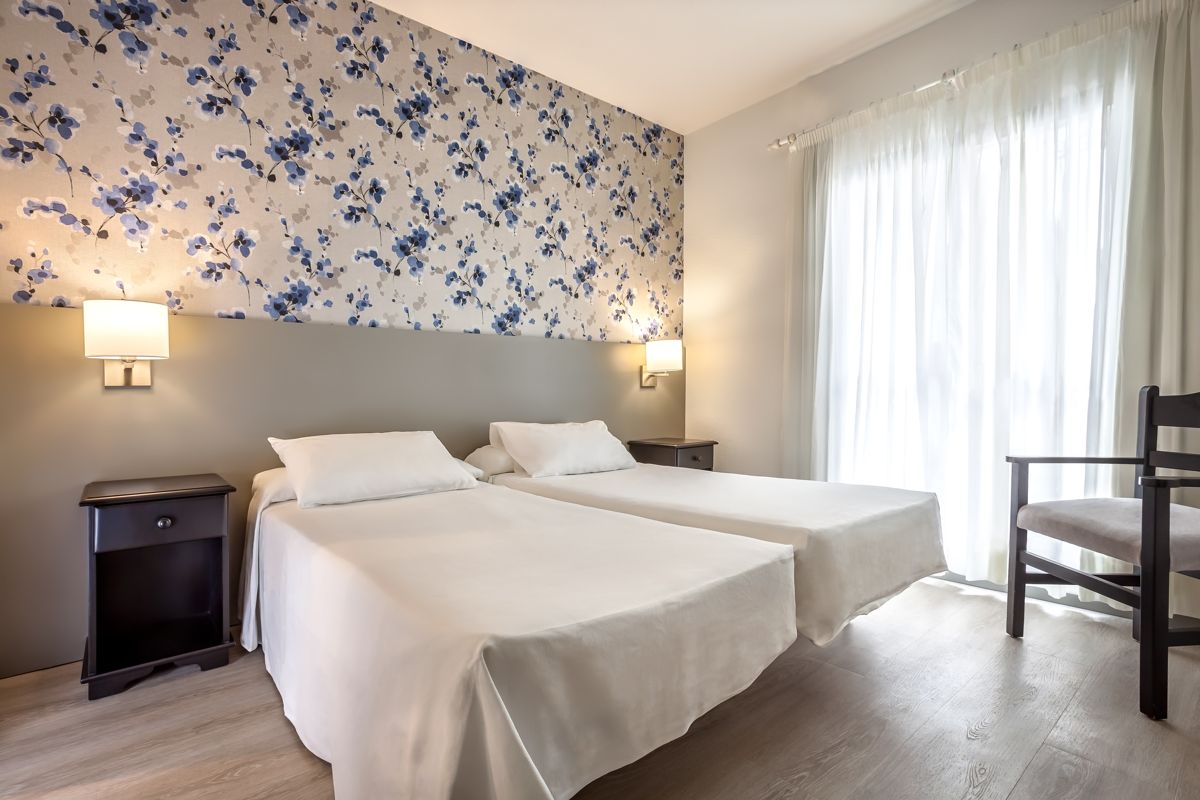 Deux lits simples dans une chambre lumineuse à Tenerife, papier peint floral.