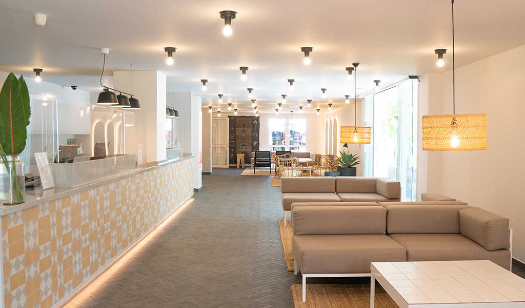 Hall d'accueil d'un hôtel à Tenerife avec canapés et comptoir lumineux.