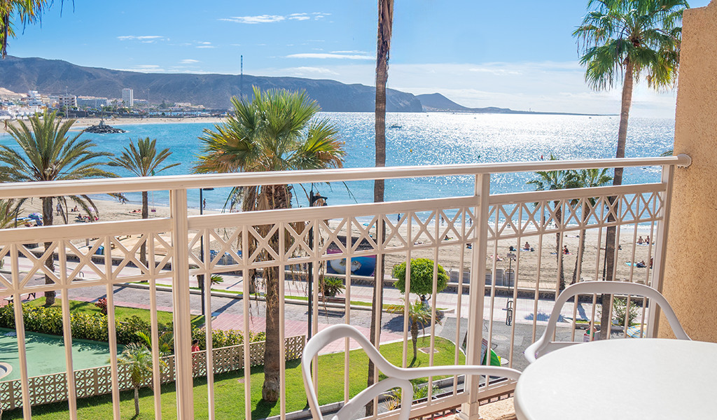 Vue sur la plage avec palmiers à Tenerife depuis un balcon ensoleillé.