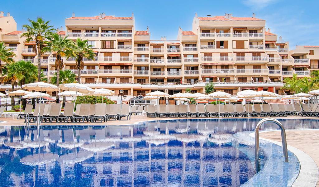Piscine avec parasols et immeuble en arrière-plan à Tenerife.