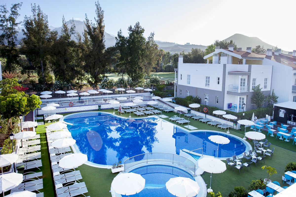 Piscine extérieure d'un complexe à Tenerife entourée de chaises longues blanches.