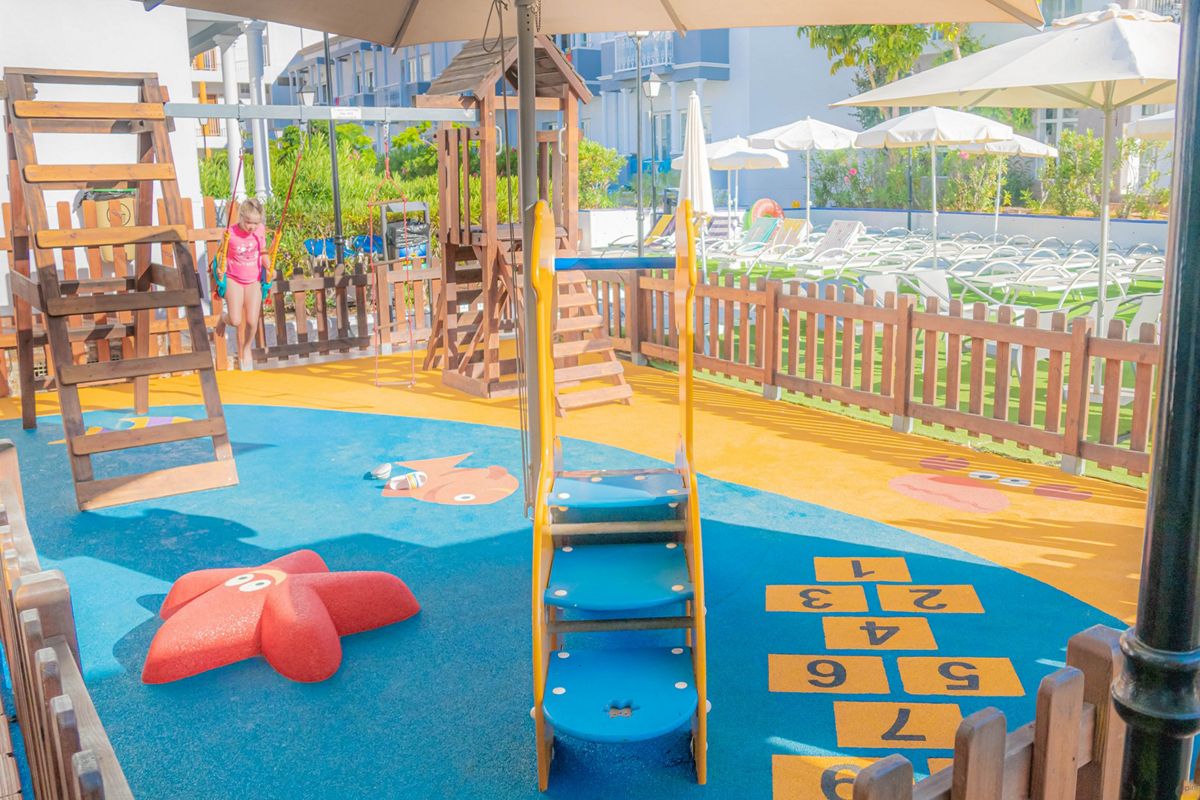 Aire de jeux extérieur pour enfants à Tenerife, avec toboggan et marelle colorée.