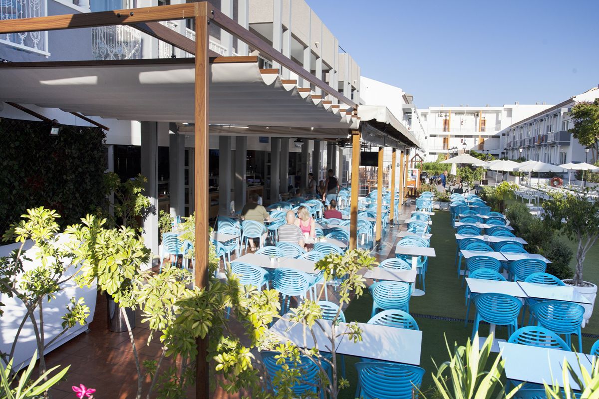 Terrasse de café à Tenerife avec des chaises bleues et tables blanches.