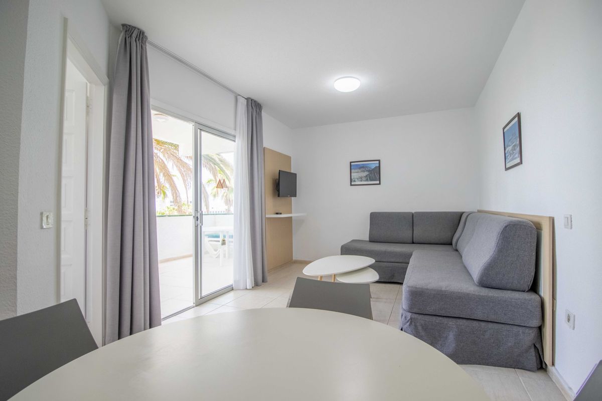 Salon moderne avec canapé gris, table basse et fenêtre donnant sur la terrasse à Tenerife.