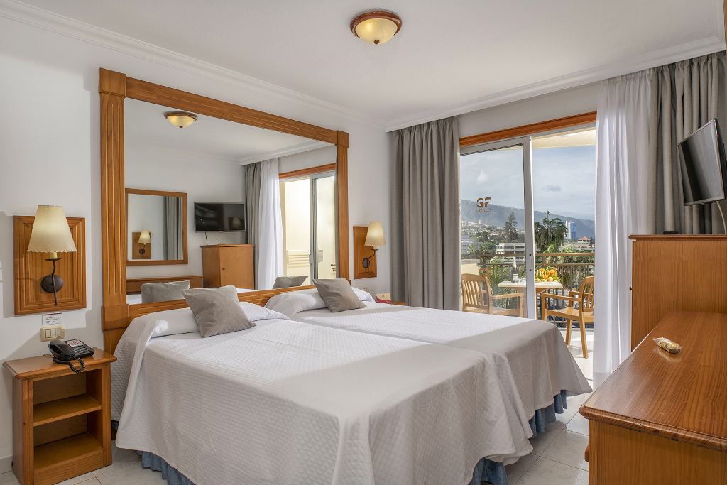 Chambre d'hôtel lumineuse à Puerto de la Cruz avec balcon et lit double.