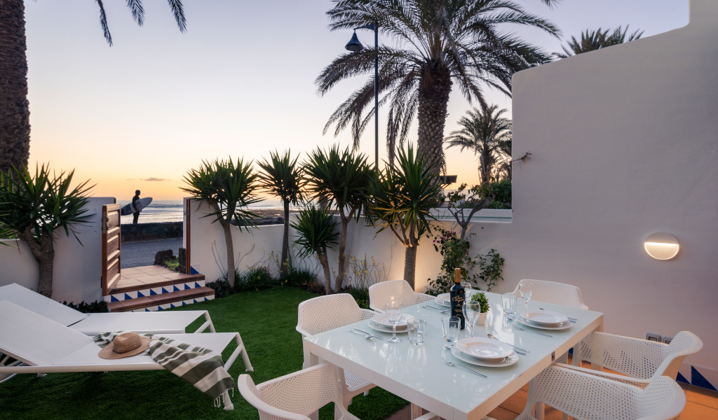 Terrasse avec table dressée, chaises blanches, vue mer au coucher du soleil à Tenerife.