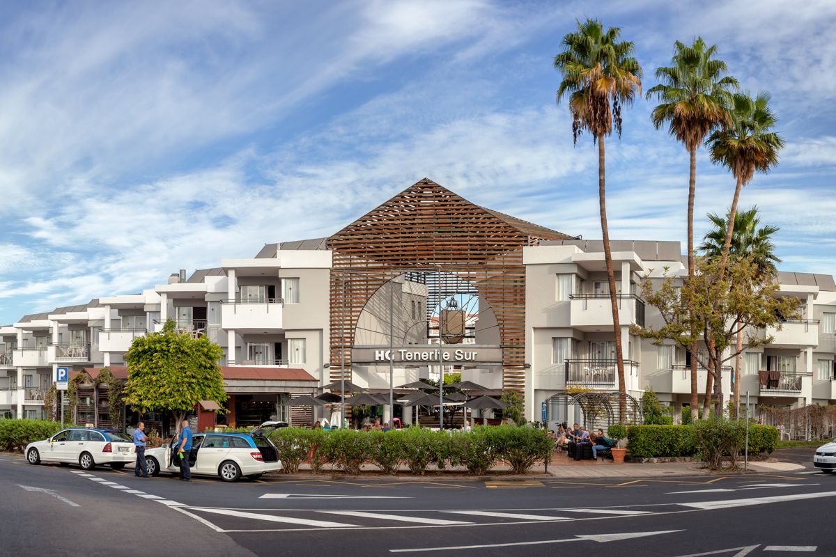 Bâtiment de l'HG Tenerife Sur avec voitures et palmiers.