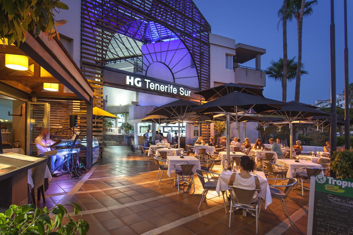 Terrasse de restaurant animée au HG Tenerife Sur, le soir.