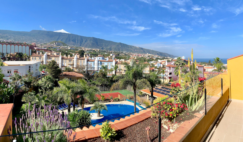 Vue sur Puerto de la Cruz avec le mont Teide en arrière-plan sous un ciel bleu.
