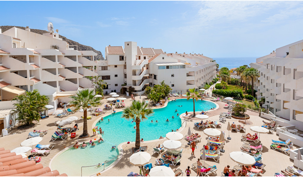 Piscine extérieure avec vacanciers entourée d'immeubles à Tenerife.