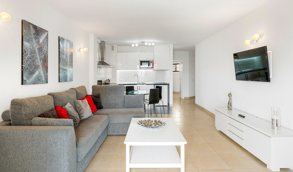 Salon moderne avec canapé, table basse, télévision murale, vue sur cuisine à Tenerife.