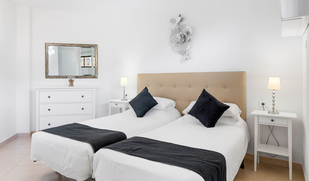 Deux lits simples avec couvertures noires dans une chambre à Tenerife.