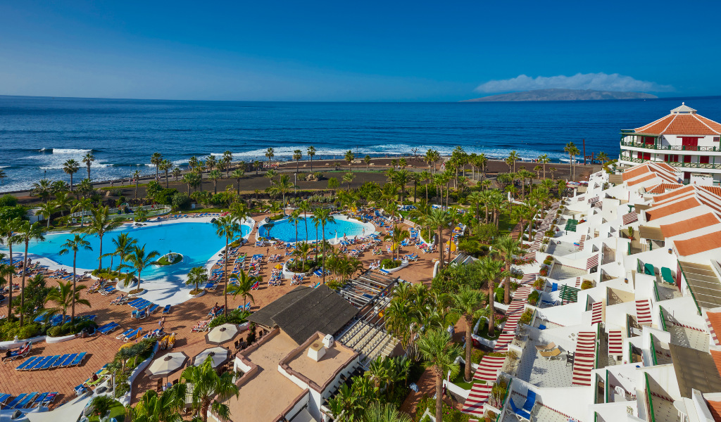 Vue aérienne d'un complexe hôtelier avec piscines à Tenerife, face à l'océan.