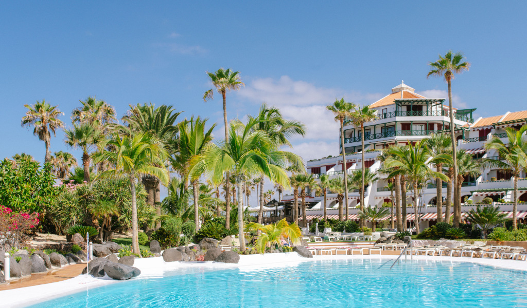 Piscine entourée de palmiers avec hôtel en arrière-plan à Tenerife.