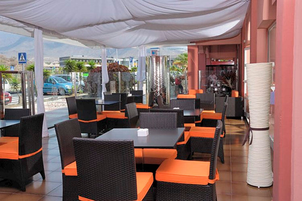 Terrasse de restaurant à Tenerife avec sièges orange et table noire.