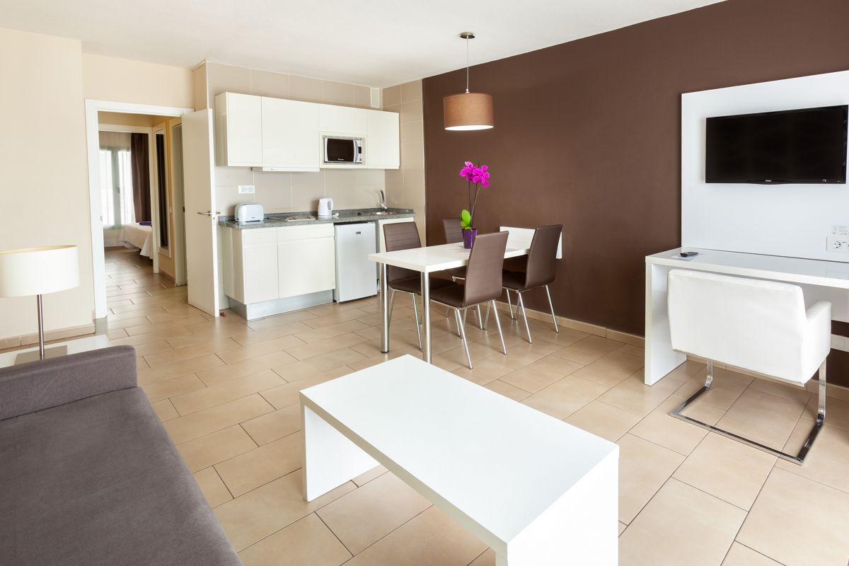 Salon moderne avec cuisine ouverte, table à manger et télévision à Costa Adeje, Tenerife.