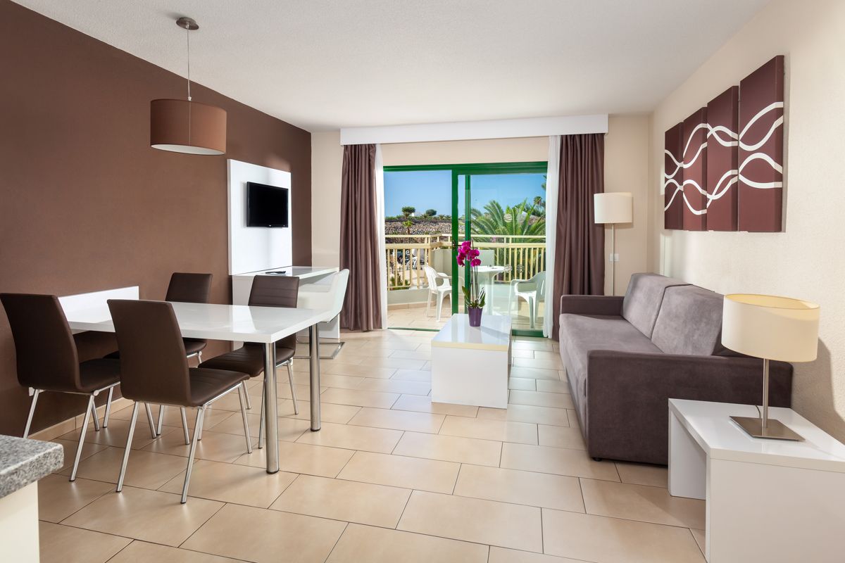 Salon moderne avec canapé, table à manger, lampe, et balcon avec vue à Tenerife.