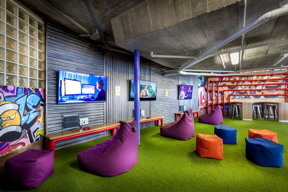 Salle de détente colorée avec écrans et poufs à Tenerife.