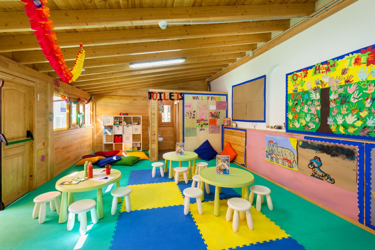Salle de jeux colorée pour enfants à Tenerife, tables rondes et coussins au sol.