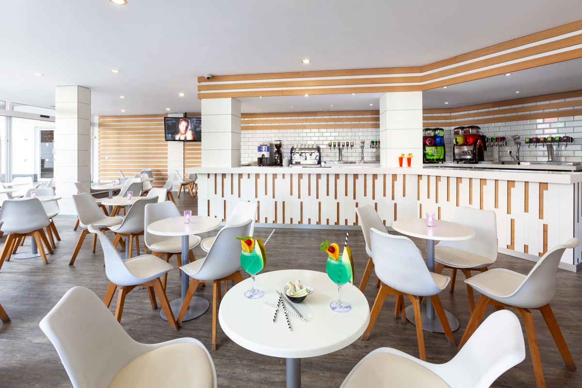 Bar moderne avec tables et chaises blanches, boissons vertes sur une table à Tenerife.