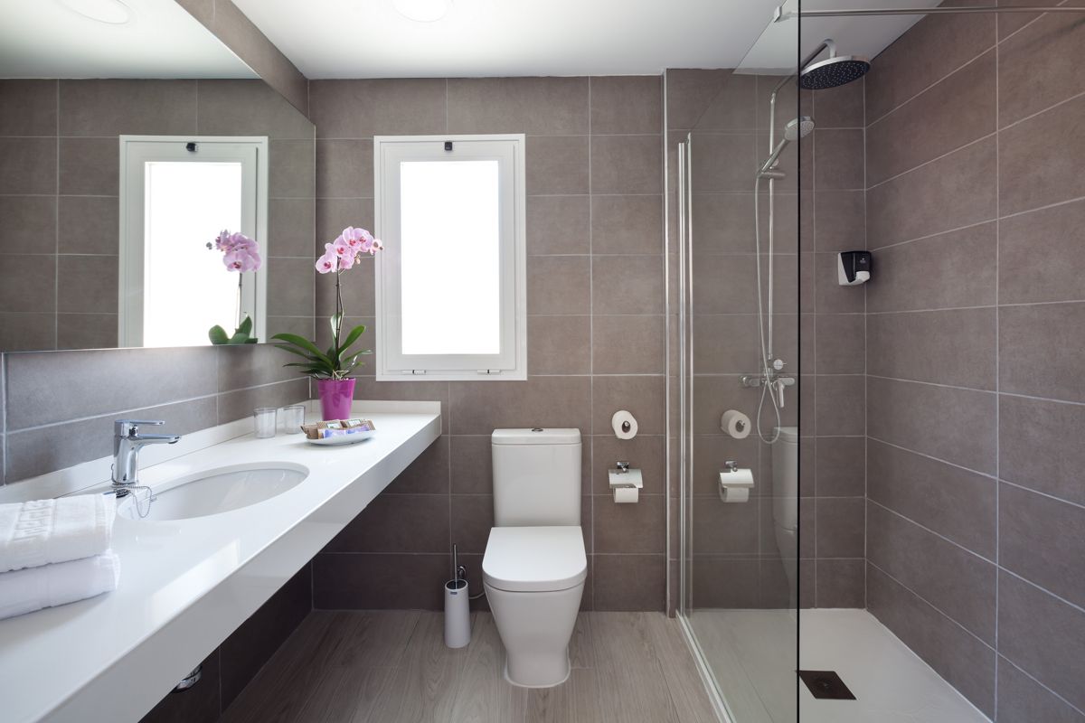 Salle de bain moderne avec douche, orchidée sur le lavabo, située à Tenerife.