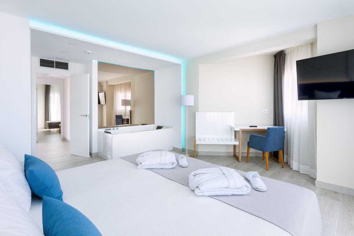 Chambre d'hôtel moderne avec lit double, chaises et télévision à Tenerife.