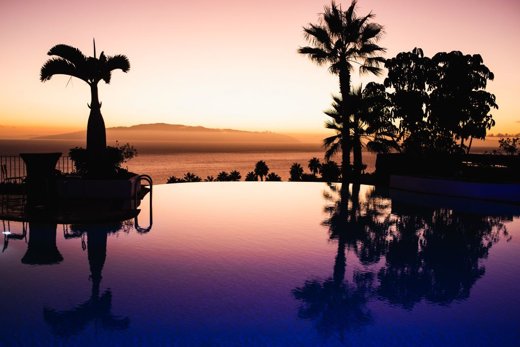 Coucher de soleil sur piscine à débordement avec vue sur océan à Tenerife.