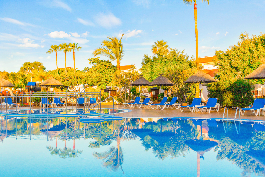 Piscine entourée de chaises longues et palmiers à Tenerife.
