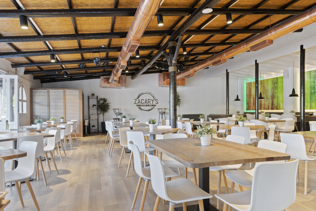 Salle à manger du restaurant Zacary's à Tenerife avec tables et chaises blanches.