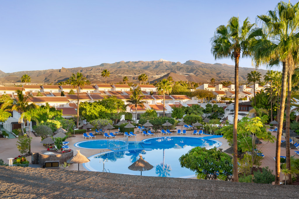 Complexe résidentiel avec piscine et palmiers à Costa Adeje, Tenerife. Montagnes à l'arrière-plan.