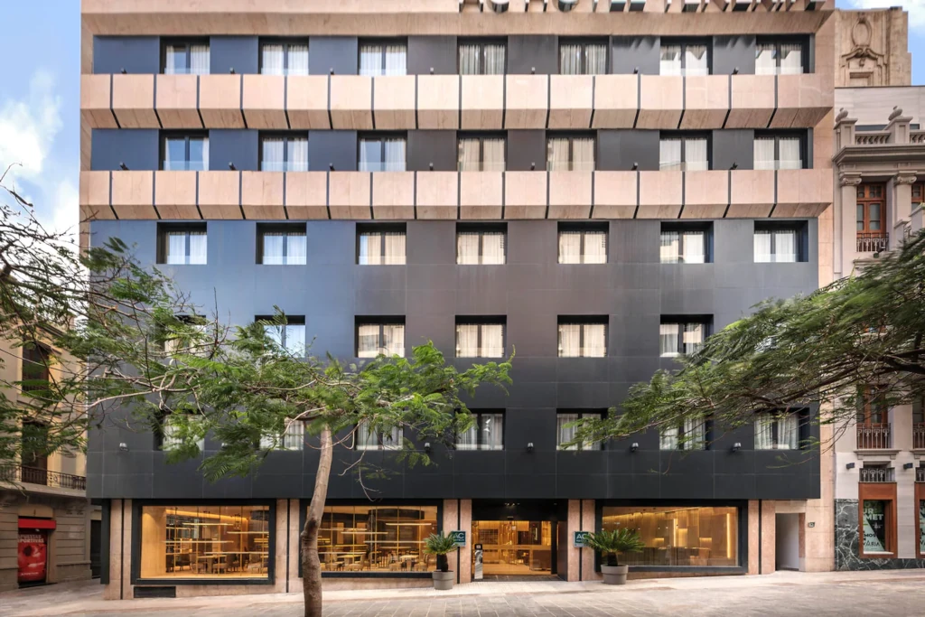 Façade d'un hôtel moderne à Santa Cruz de Tenerife, avec arbres devant.