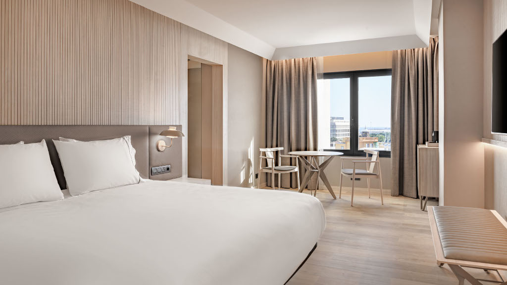 Chambre d'hôtel moderne à Tenerife avec lit, table et grande fenêtre.