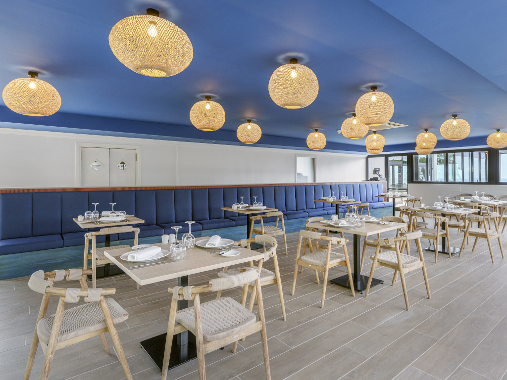Restaurant moderne avec tables et chaises en bois et plafond bleu à Tenerife.